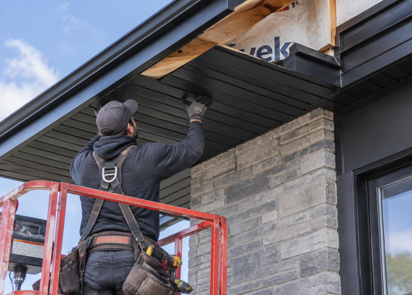 Installer fitting black aluminum soffit under a roof eave